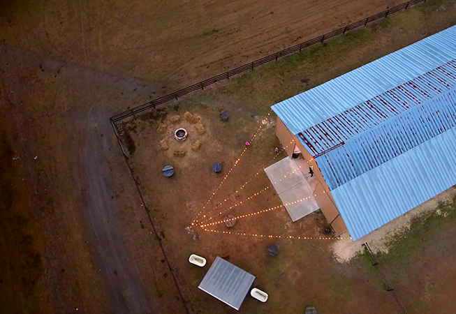 aerial shot of barn decorated with lights for a wedding