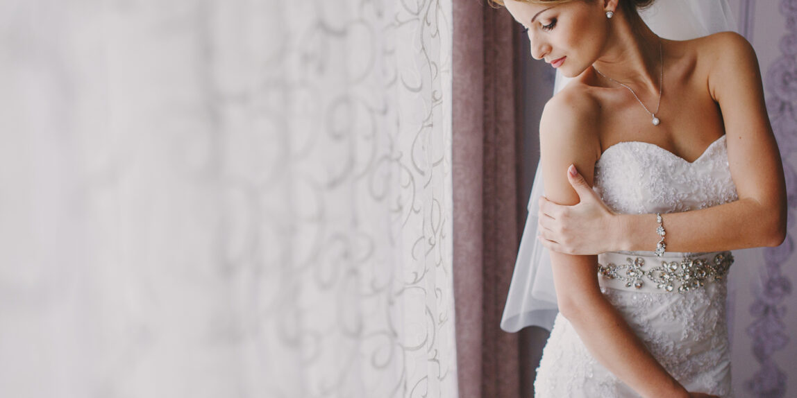 bride-standing-by-window-in-wedding-dress